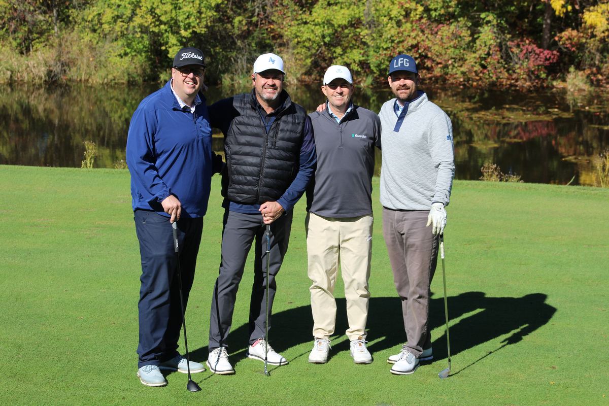 Foursome of golfers posing on the green during our charity golf tournament
